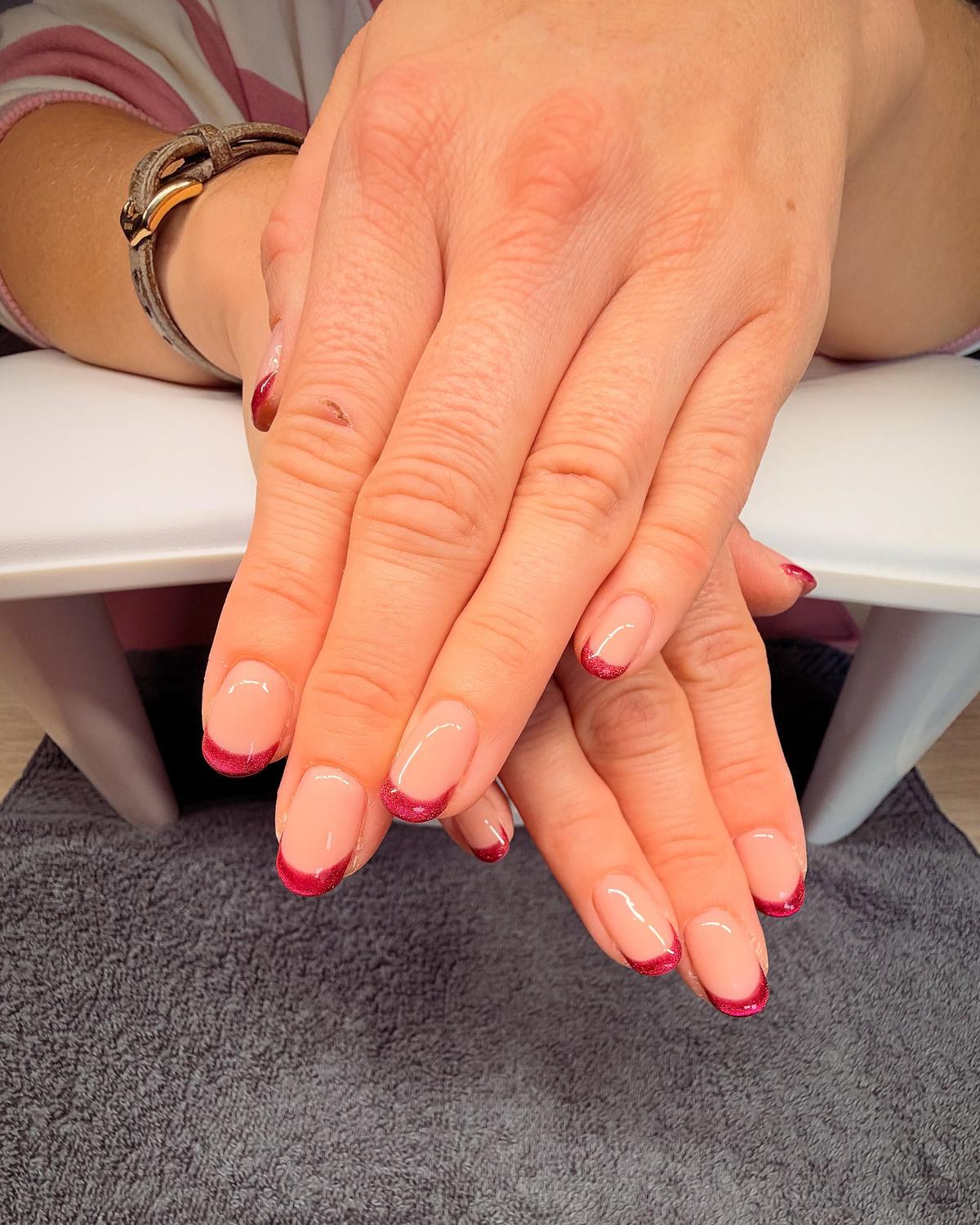 Short almond nude nails with glossy raspberry-red glitter French tips