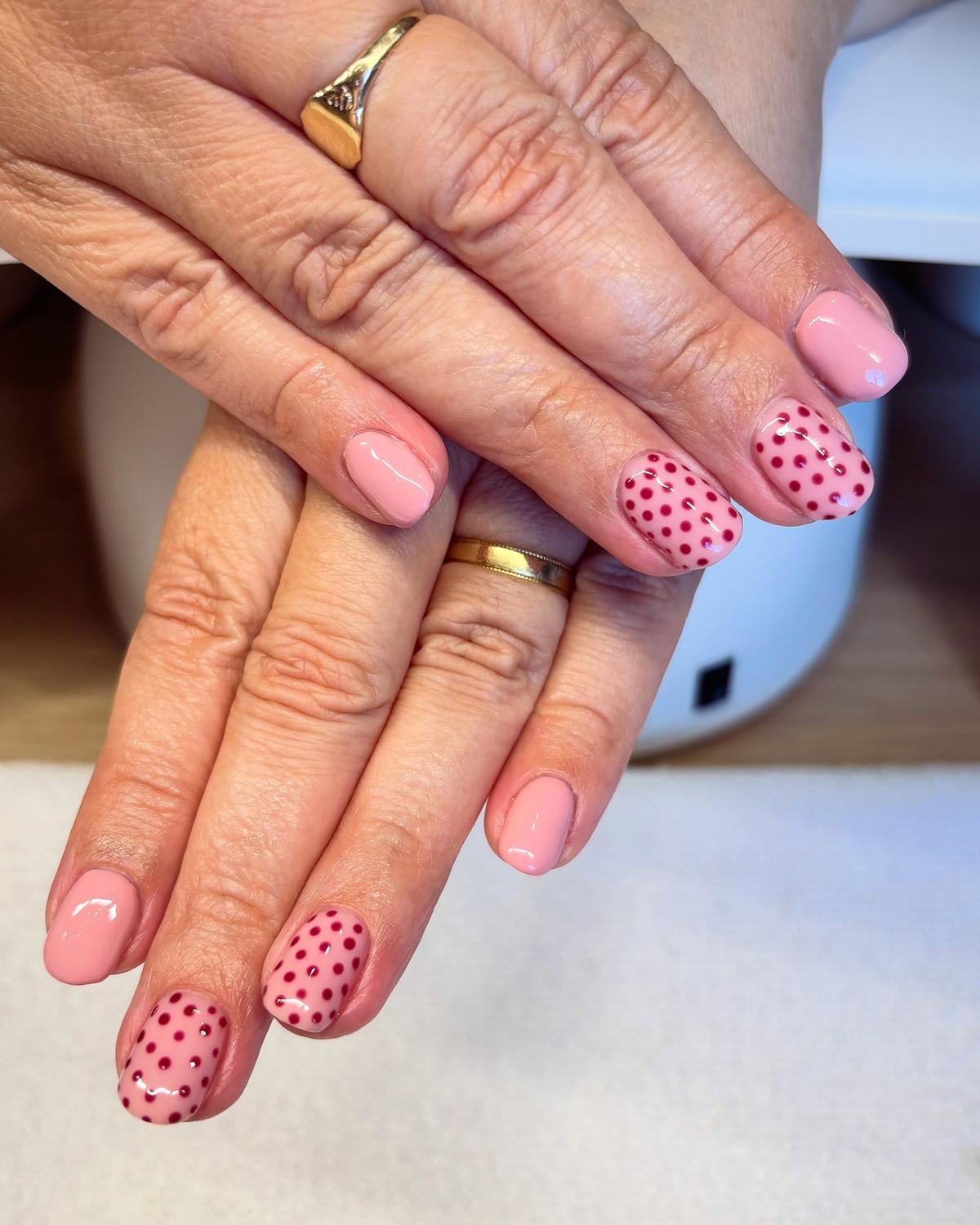 Short soft-pink gel nails with raspberry polka-dot accent nails